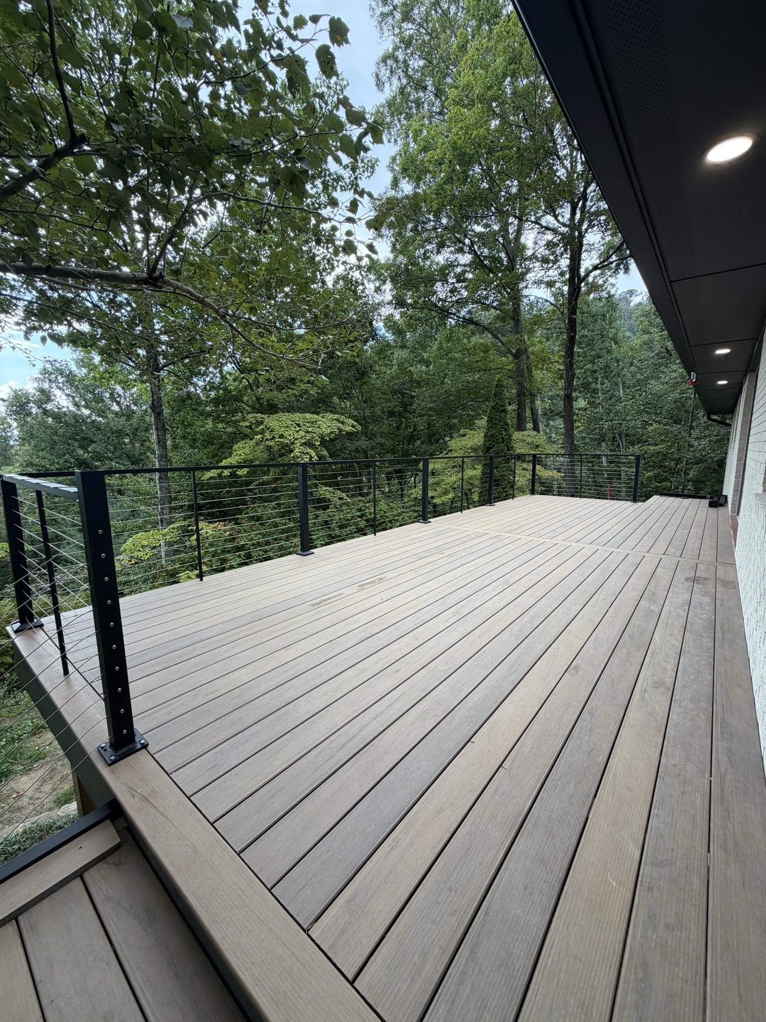 Finished deck walking surface with black cable railing and woods — built by Terra Builders AVL
